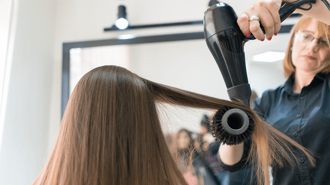 hairdresser drying another woman's hair with a hair dryer