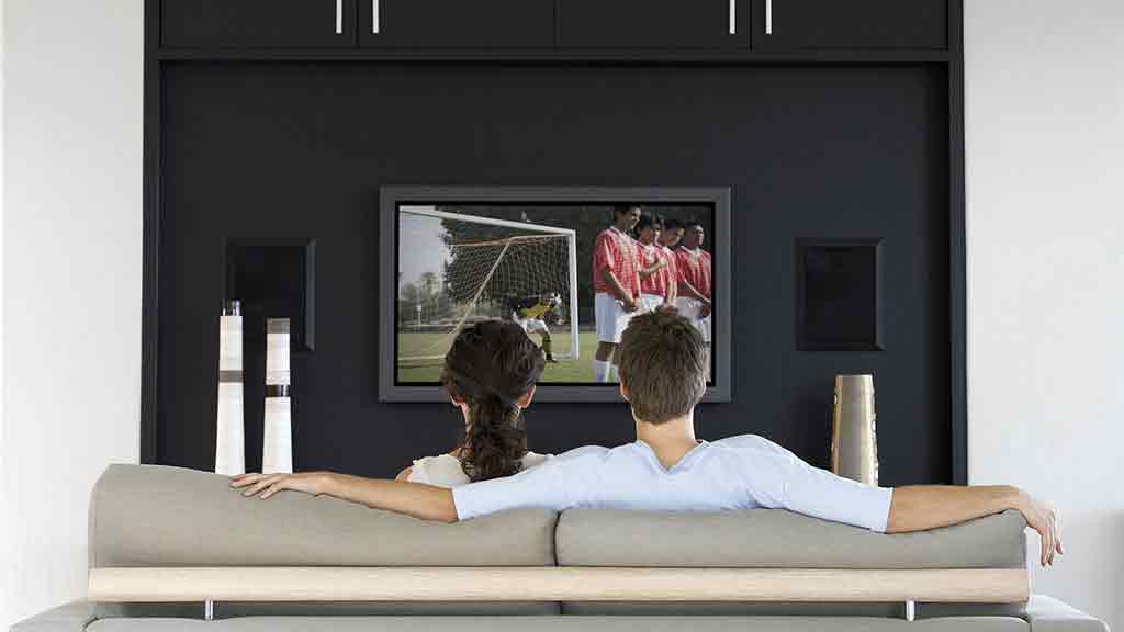 man and woman watch soccer on tv