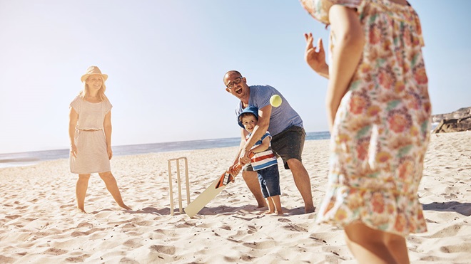 family playing cricket on beach summer topic