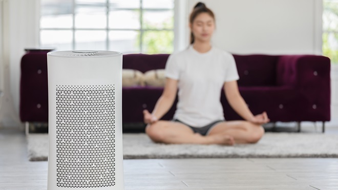 person meditating in their lounge room and using an air purifier