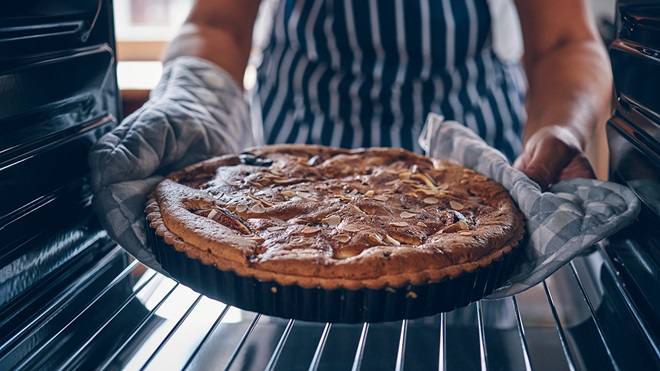 person taking fig tart out of the oven