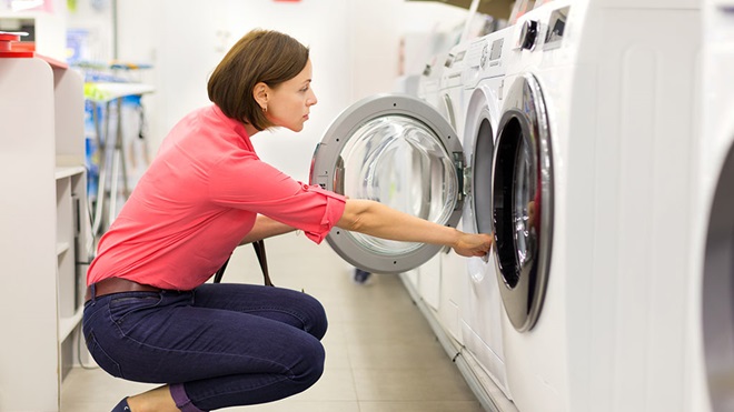 woman looking in washing machine at store