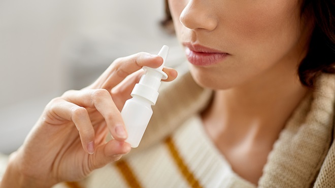 person using a tanning nasal spray