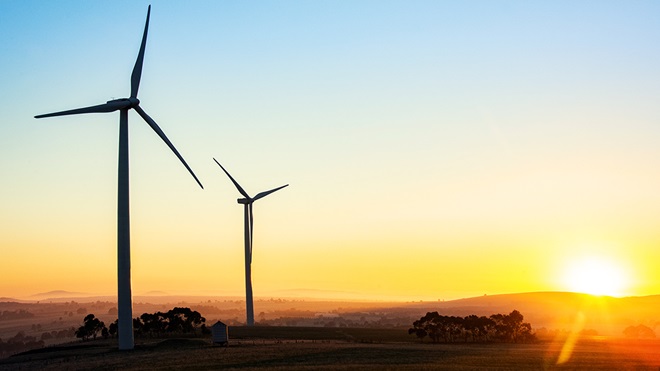 sun rising behind wind turbines in western australia