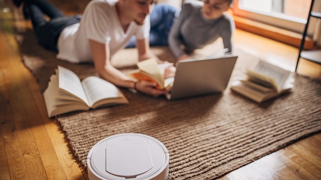 two_people_reading_and_talking_in_the_background_whie_robot_vacuum_cleans
