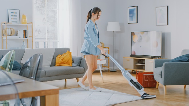 woman using a stick vac at home lead