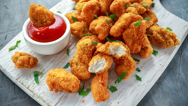 chicken nuggets on board with tomato sauce