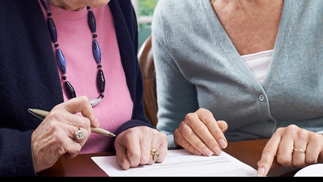 person instructing elderly parent to sign documents