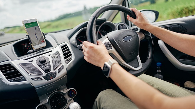 person driving a car using a car navigation app on their phone