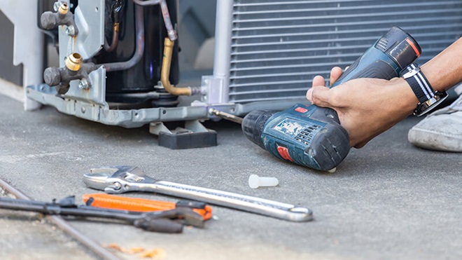 Closeup of someone repairing an appliance with a drill