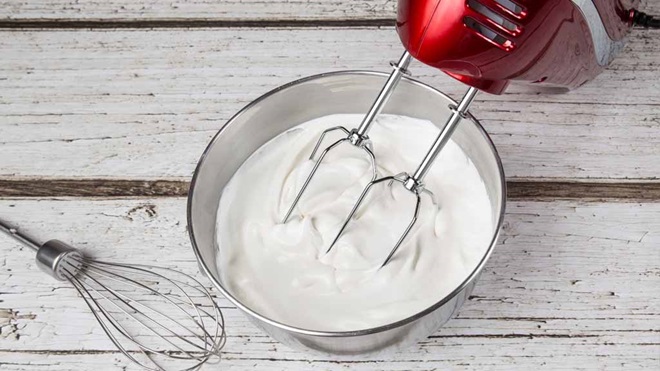 red mixer in bowl of whipped cream