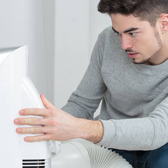 man using a portable air conditioner at home sq