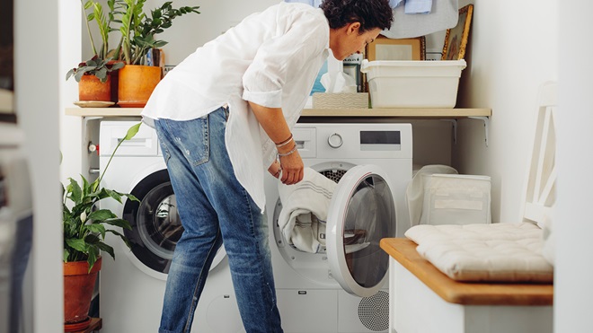 woman putting clothes into a front loading washing machine