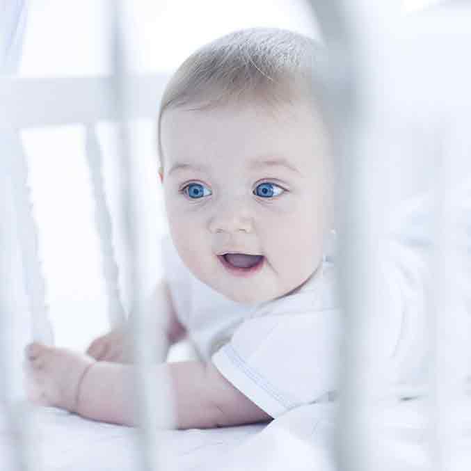 baby looking out of a cot square