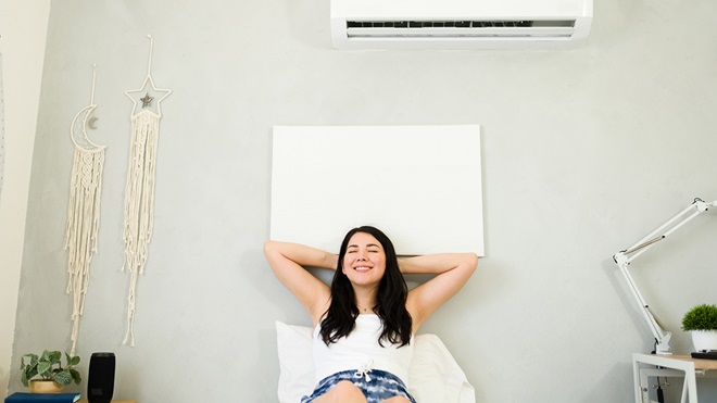 woman keeping cool in bedroom with airconditioning