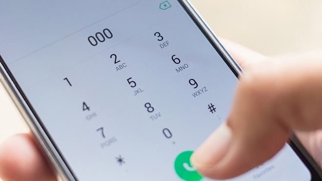 closeup of someone dialling 000 on smartphone