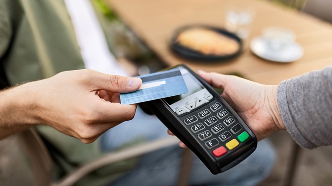 person making a payment with debit card at cafe