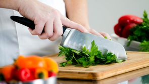 person using knife utensil to chop parsley