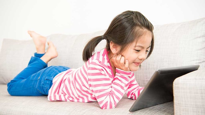 child with tablet on sofa