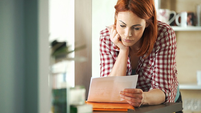 person looking at letter in their kitchen